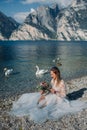 A girl in a smart white dress is sitting on the embankment of lake Garda.A woman is photographed against the background of a Royalty Free Stock Photo