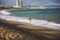 Girl with a smartphone standing on the beach on sunny day. Stylish hipster near the waves on the sea. Woman talking. Holiday