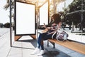 Girl with smartphone and two billboard templates in bus stop Royalty Free Stock Photo