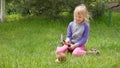 Girl smashes coconut with a heavy iron hammer sitting on the grass 01 Royalty Free Stock Photo