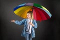 The girl smiles, holds a multicolored rainbow umbrella in her hands and checks if it is raining Royalty Free Stock Photo