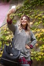 The girl smiles and is photographed against the background of a wall with ivy. Autumn Selfie Royalty Free Stock Photo