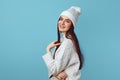 Girl smiles pleasantly at camera, wears white hat and white oversized sweater