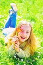 Girl on smiling face holds red tulip flower, enjoy aroma. Girl lying on grass, grassplot on background. Youth and