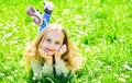 Girl on smiling face spend leisure outdoors. Heyday concept. Child enjoy spring sunny weather while lying at meadow