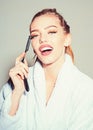 Girl on smiling face wears bathrobe, grey background. Lady play with sharp blade of straight razor. Barber concept