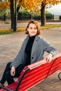 Girl smiling in gray coat sitting on bench in alley