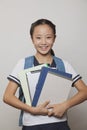 Girl smiling and holding bunch of notebooks and digital tablet, Studio