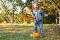 Girl smiling laughs and plays with pumpkin. Little happy girl stands on large orange pumpkin outside. The child plays