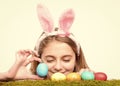 Girl smiling with painted eggs on green grass, spring