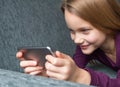 Girl is smiling while using a smartphone Royalty Free Stock Photo