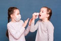 Girl Sneezes Hiding Behind A Handkerchief. The Second Girl Protects Herself From Her With A Mask And Hands. Infecting Children