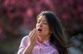 Girl sneezing in front of blooming tree in spring Royalty Free Stock Photo