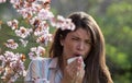 Girl sneezing in front of blooming tree in spring Royalty Free Stock Photo