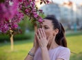 Girl sneezing in napkin in front of blooming tree in spring Royalty Free Stock Photo