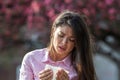 Girl sneezing in napkin in front of blooming tree in spring Royalty Free Stock Photo