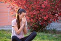 Girl sneezing in napkin in front of blooming tree in spring