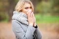 Girl sneezing in tissue. Young woman blowing her nose on the park. Woman portrait outdoor sneezing because cold and flu Royalty Free Stock Photo