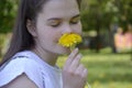 A girl sniffs a yellow flower, a dandelion