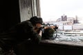 Girl sniper looks through the scope. Girl warrior directs his rifle through the broken window of an abandoned building. Military Royalty Free Stock Photo