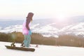 Girl snowboarder stand on the background of snow-capped mountains, preparing for slalom. Modern sports equipment for winter sports