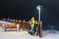 Girl snowboarder stands on a hillside against the dark sky