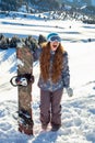 Girl snowboarder stands mountain top with snowboard in hands.