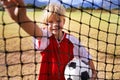 Girl, soccer player and ball on goal net, smile and happy for game, field and child. Outdoor, playful and sport for Royalty Free Stock Photo