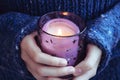 Girl in soft warm dark blue knitted sweater holds in hands burning candle Royalty Free Stock Photo