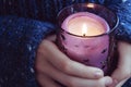 Girl in soft warm dark blue knitted sweater holds in hands burning candle Royalty Free Stock Photo
