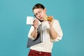 Girl speaks on the phone, holds documents under the armpit and eats a sandwich Royalty Free Stock Photo