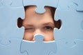 The girl spies through a blue puzzle