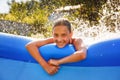 A girl splashes in an inflatable pool in the garden on a sunny summer day Royalty Free Stock Photo