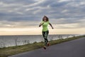 Girl in sports leggings and a green t-shirt running along the wa