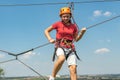 A girl in a sports park on a cable car overcomes obstacles