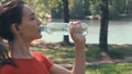 A girl after sports, unscrews the lid and drinks water on the street.