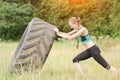 Girl in sportswear raises tire. Street workout.