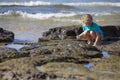 Girl Squatting on Rocks at Sea