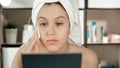 Girl squeezes black dots on her nose. Attractive woman in towel on her head looks in mirror and presses on skin on bridge of her