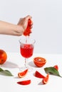 The girl squeezes the juice from the orange hand in a glass. Cut oranges on a light background Royalty Free Stock Photo