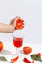 The girl squeezes the juice from the orange hand in a glass. Cut oranges on a light background Royalty Free Stock Photo