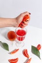 The girl squeezes the juice from the orange hand in a glass. Cut oranges on a light background Royalty Free Stock Photo