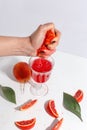 The girl squeezes the juice from the orange hand in a glass. Cut oranges on a light background Royalty Free Stock Photo