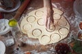 The girl squeezes round shapes out of the dough with a glass