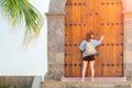 Girl stand in front of large old wooden door of ancient building, Tourist near entrance to castle. Palm tree and aged Royalty Free Stock Photo