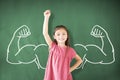 Girl standing against chalkboard and strong winner concept