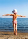 Girl standing on the beach in a striped bathing suit Royalty Free Stock Photo