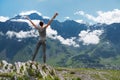 Girl standing edge of cliff and looking at mountain landscape