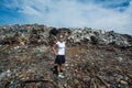 Girl standing in front of trash mountain at garbage dump