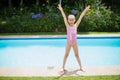 Girl standing with her hands raised near swimming pool Royalty Free Stock Photo